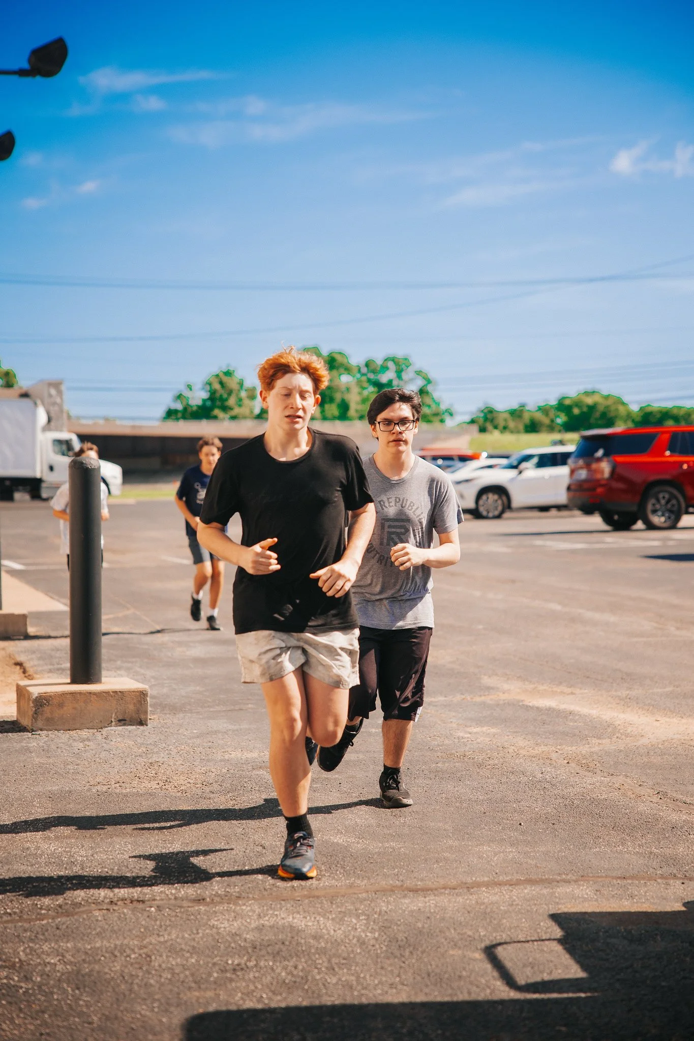 People jogging in a parking lot on a sunny day.