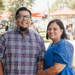 A man and a woman posing outdoors at a park or outdoor event, smiling at the camera.