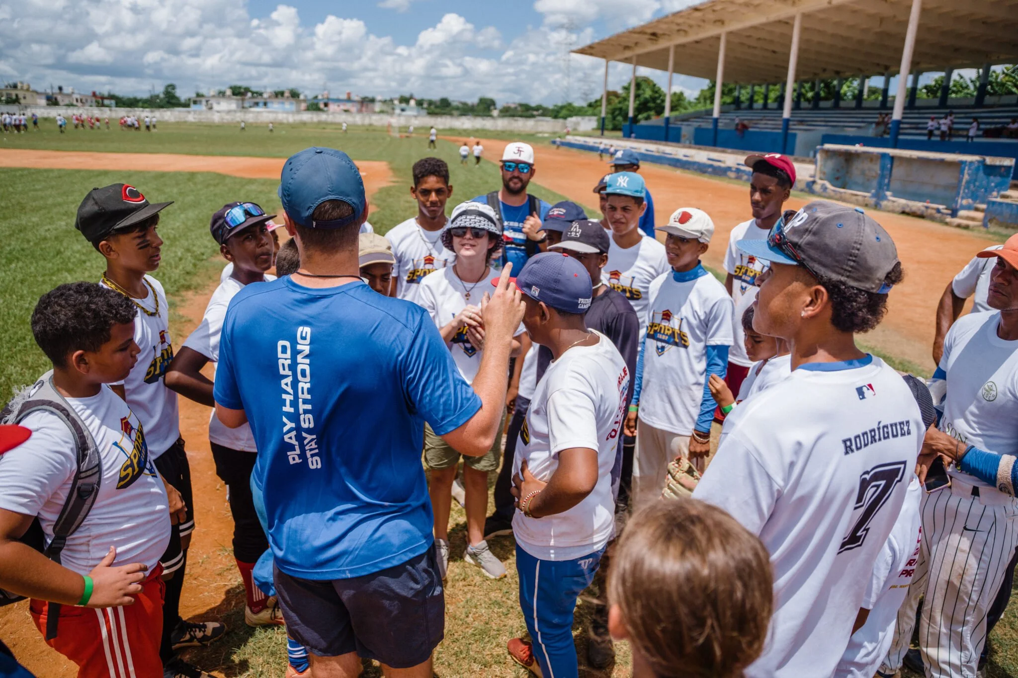 A baseball coach giving instructions to a group of young players on a baseball field during the day.