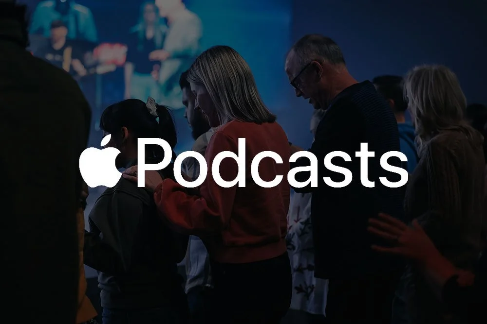 People standing in a line, praying or meditating in a dark room with a large screen displaying a video in the background, overlayed with Apple Podcasts logo and text.