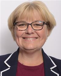 Close-up of an elderly woman with glasses and a black headband, smiling gently.