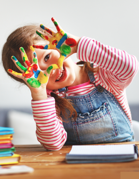 Happy child with painted hands enjoying creative play at Kid Star Daycare Center in Paw Paw, Michigan