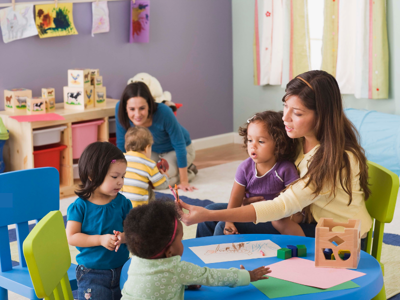 Warm, consistent caregivers engaging with children during art time at Kid Star Daycare Center in Paw Paw, Michigan.