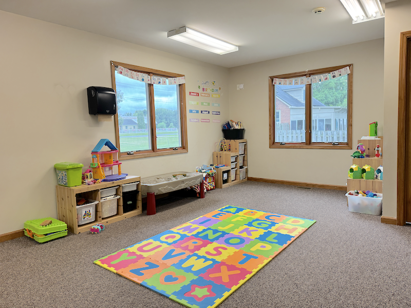 Safe, well-organized Kid Star Daycare classroom with soft alphabet mat, child-height storage, and age-appropriate toys in Paw Paw, Michigan.