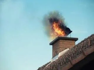 Un feu qui brûle dans une cheminée sur le toit d'une maison.