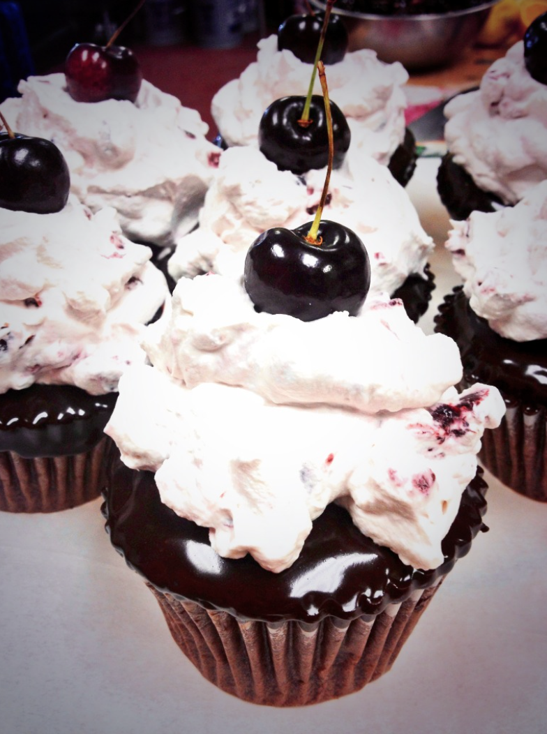 Dark Chocolate Cupcakes, topped with Dark Chocolate Ganache and a Cherry Whipped Cream Compote.