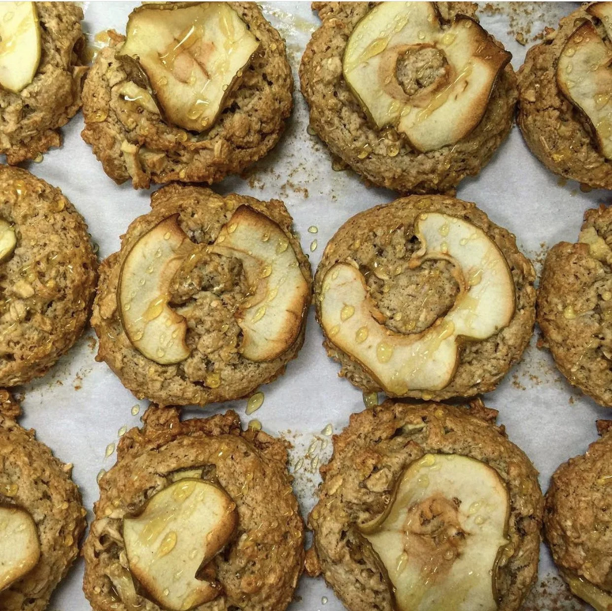 Close-up of baked oatmeal muffins topped with slices of pear and drizzled with honey.