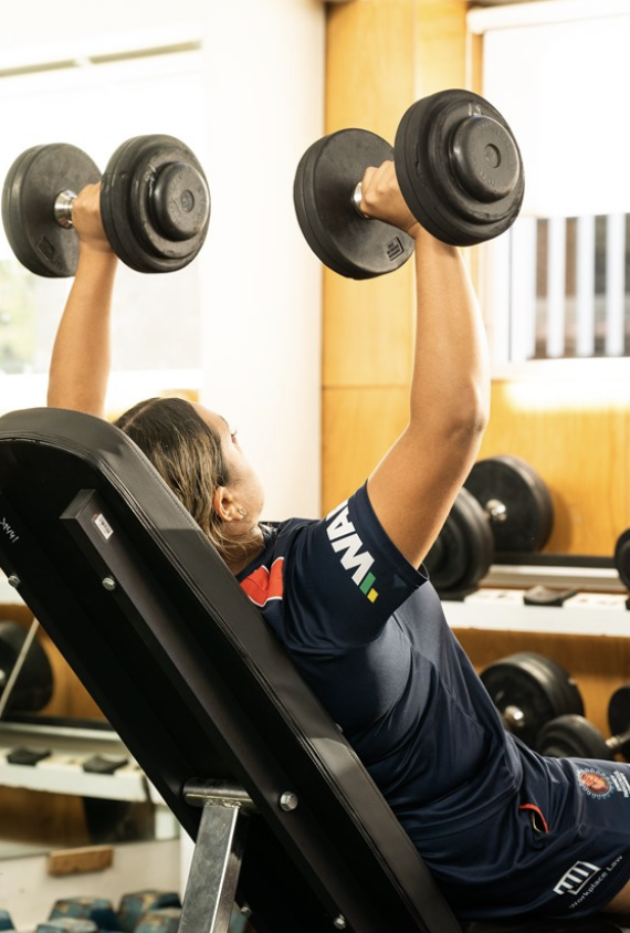 Athlete performing an incline dumbbell press during a strength and conditioning session.