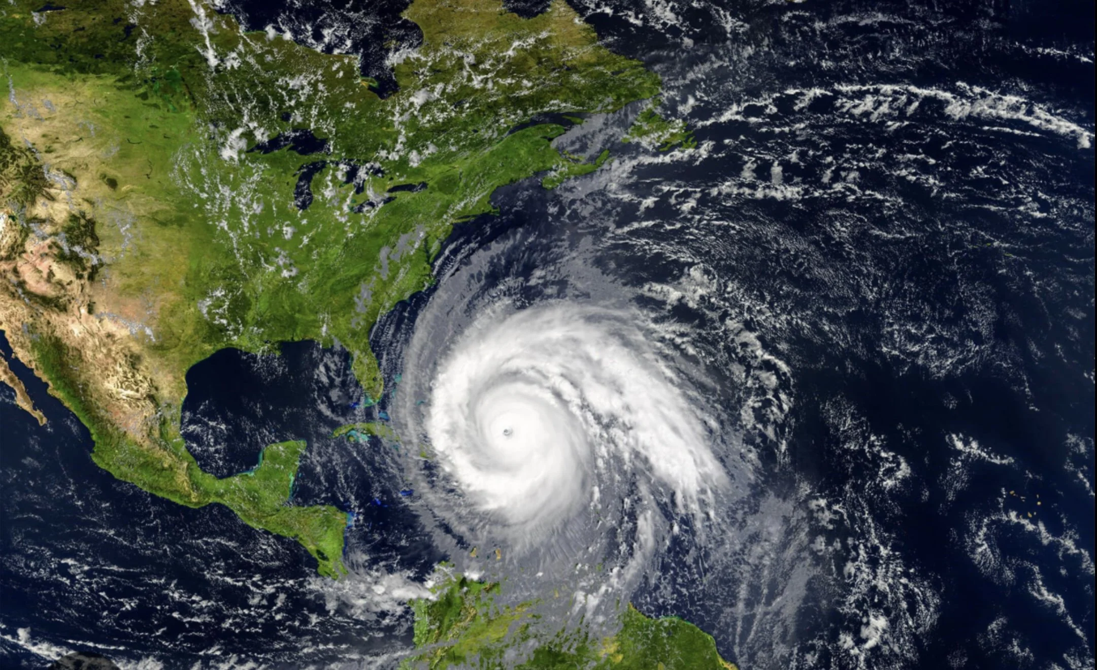 Satellite image showing a hurricane approaching the eastern coast of the United States, with parts of the southeastern U.S. and the Caribbean visible.