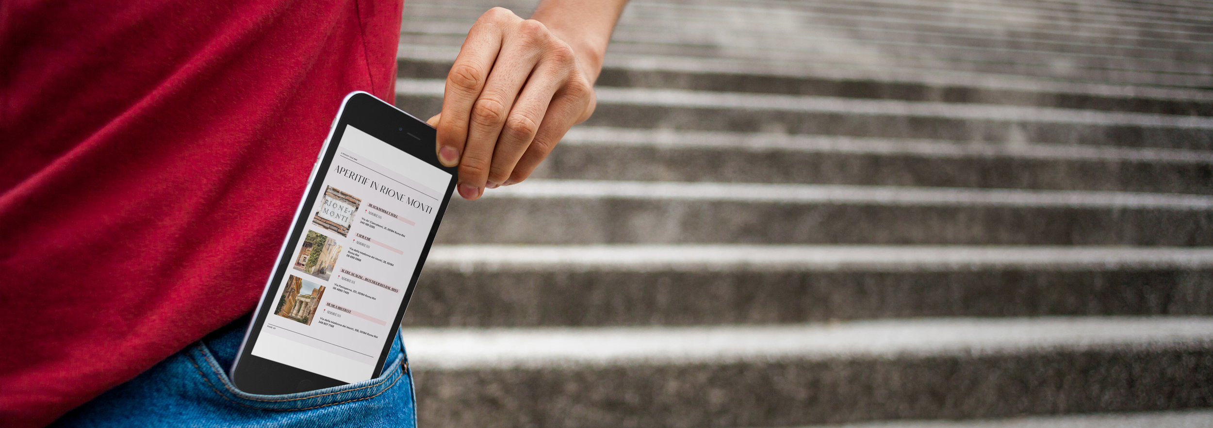 Persona con maglietta rossa che tiene uno smartphone con una pagina web di eventi culturali e monumenti in evidenza, vicino a delle scale.