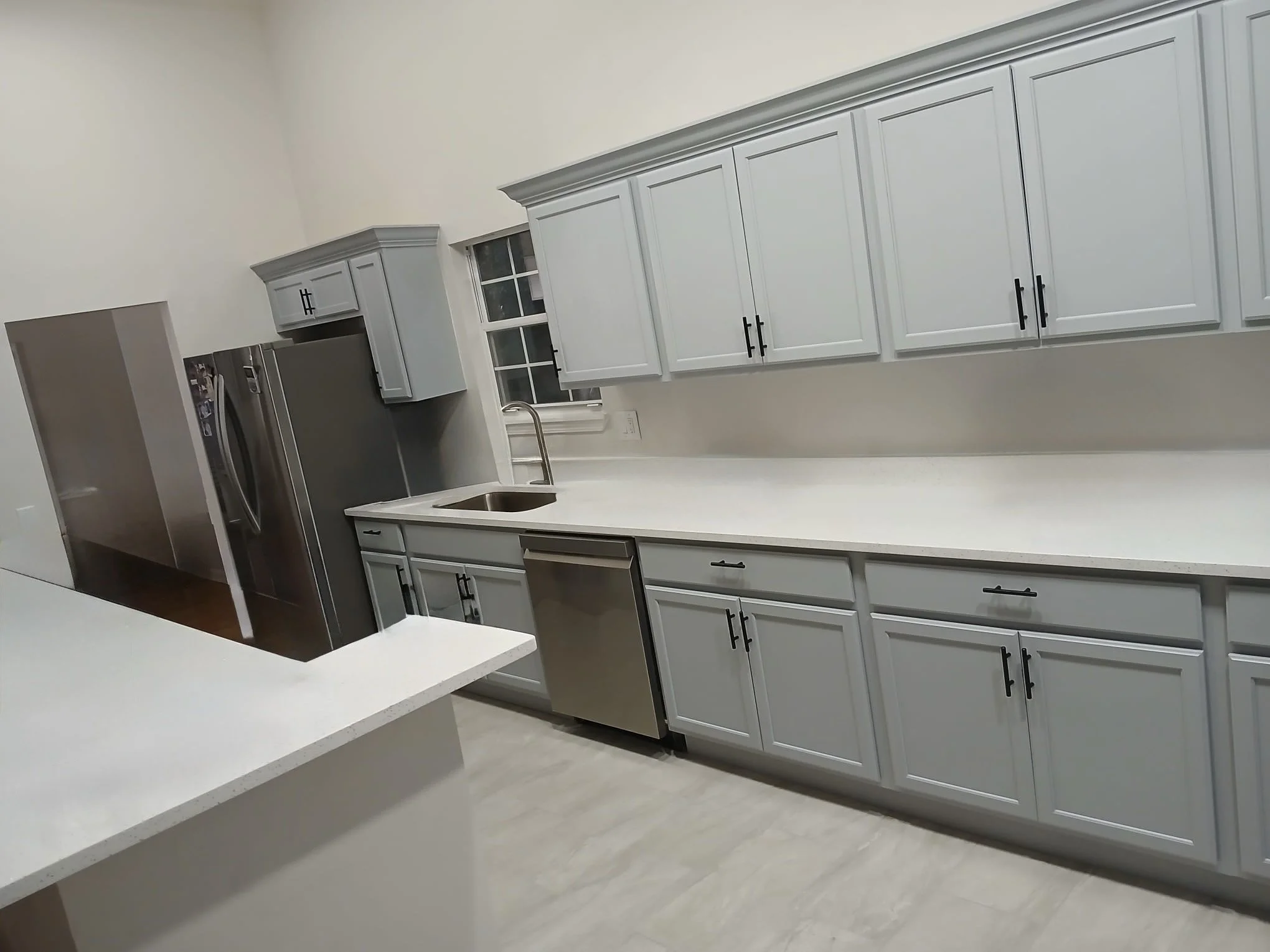 Modern kitchen with white cabinets, stainless steel appliances, a double refrigerator, and a white countertop.