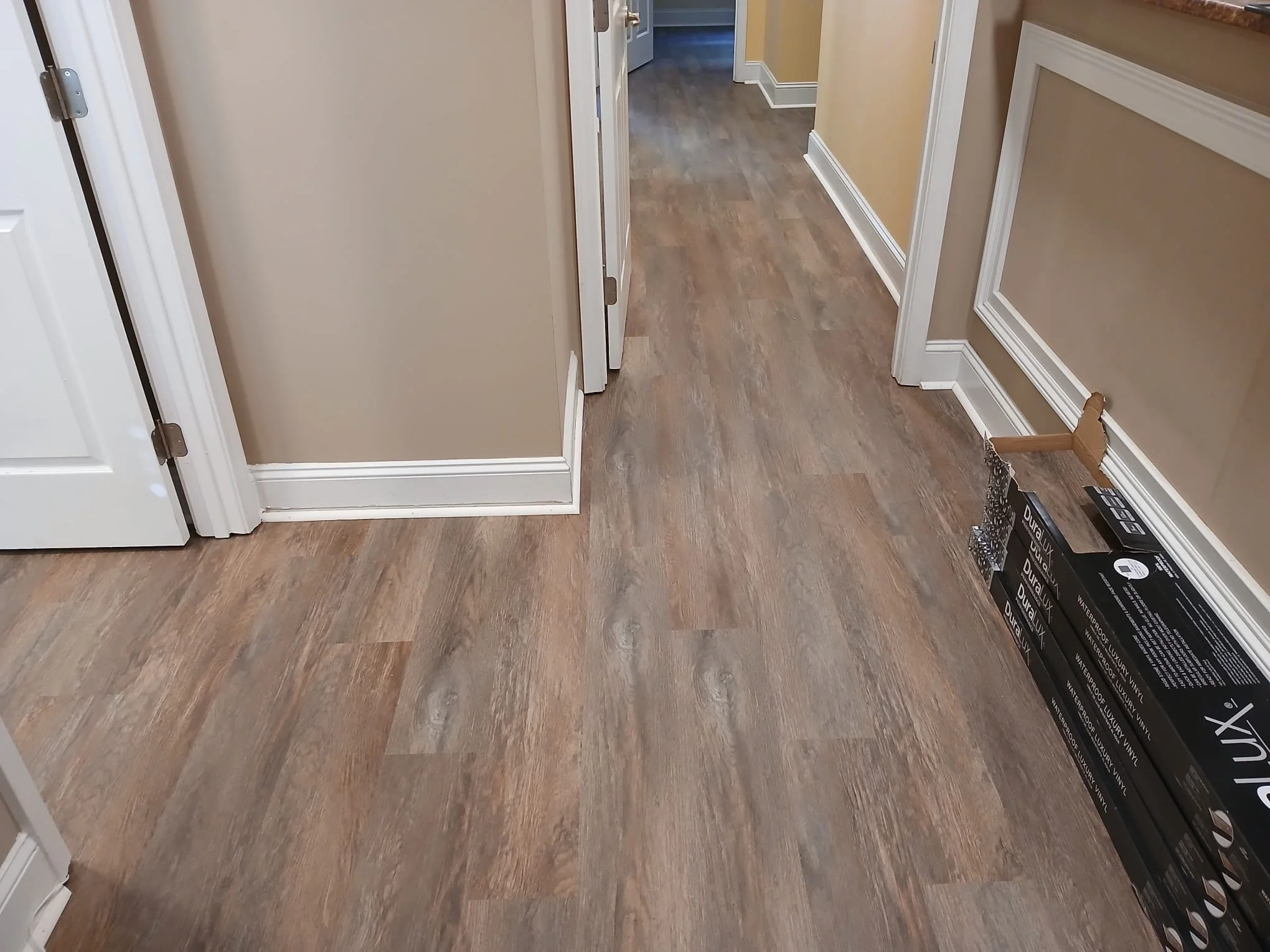 Empty kitchen floor with beige walls, white trim, and a box leaning against the wall.