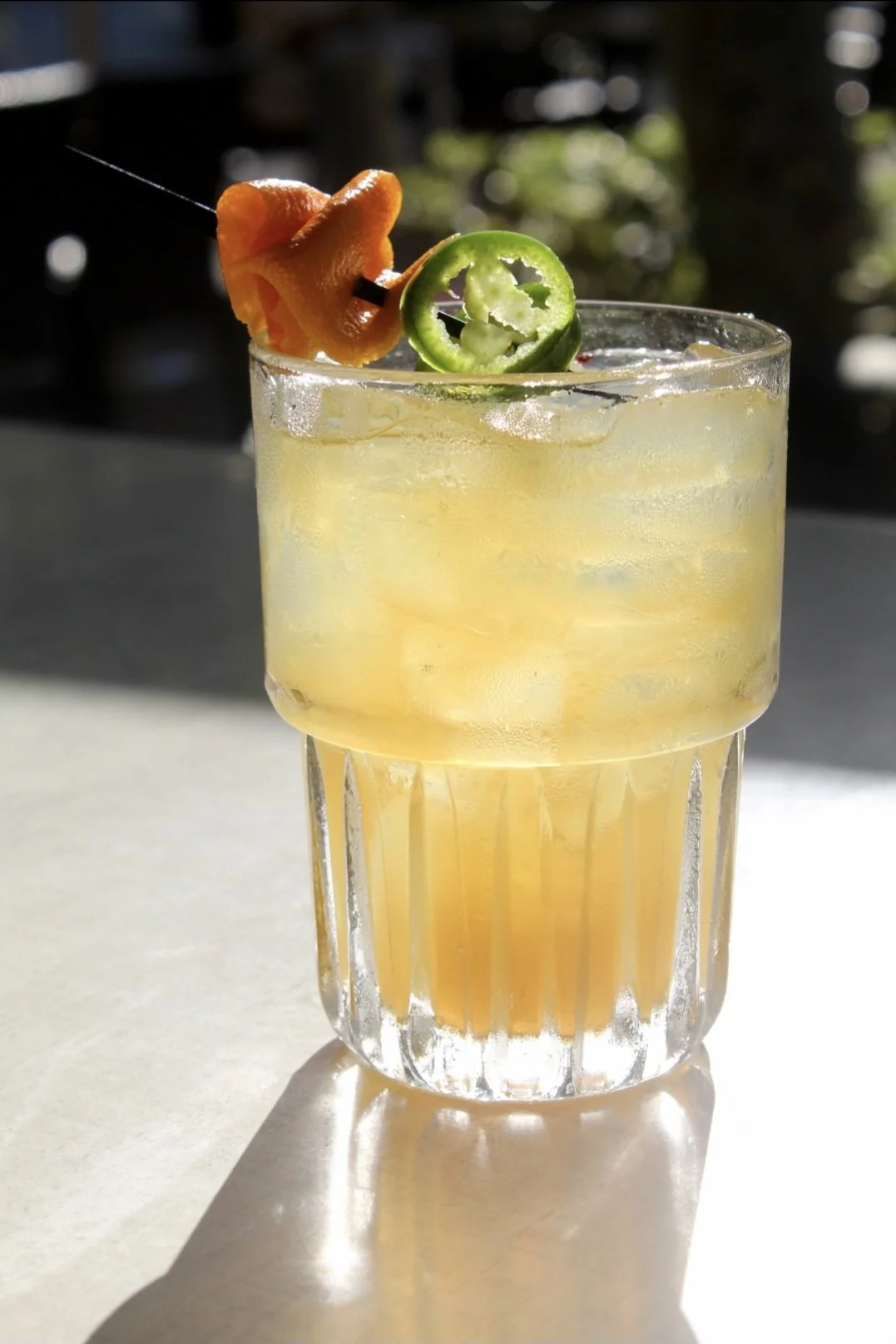 Cool Burn: A bold sip built on bourbon, fresh cucumber and jalapeno, layered with the smokey warmth of a chili liqueur, softened with honey, and brightened by the zest of an orange ribbon.