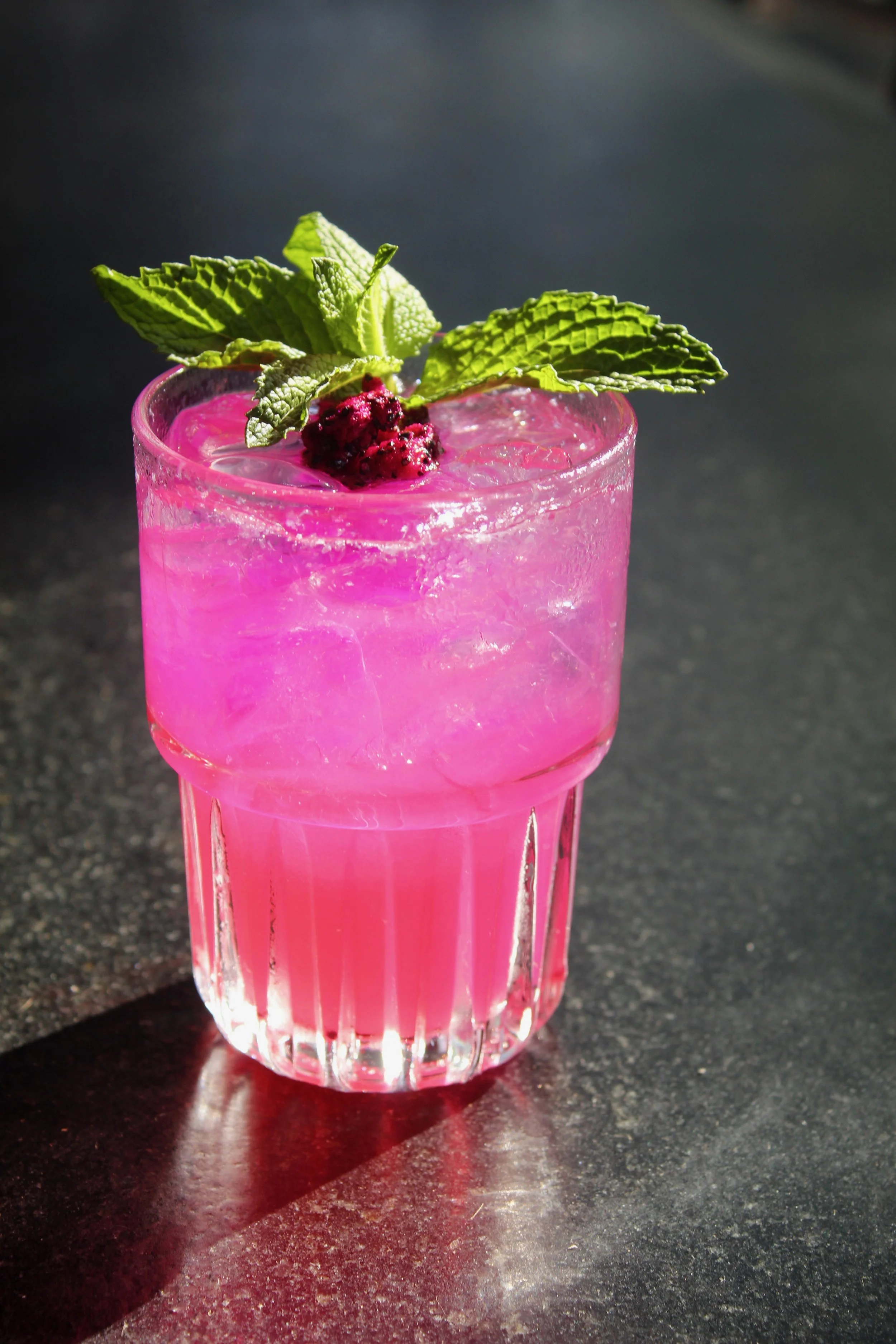 Dragon Drop: A radiant gin cocktail with luscious dragon fruit, zesty lemon, and club soda, topped with a fragrant mint sprig and mini dragon fruit cubes
