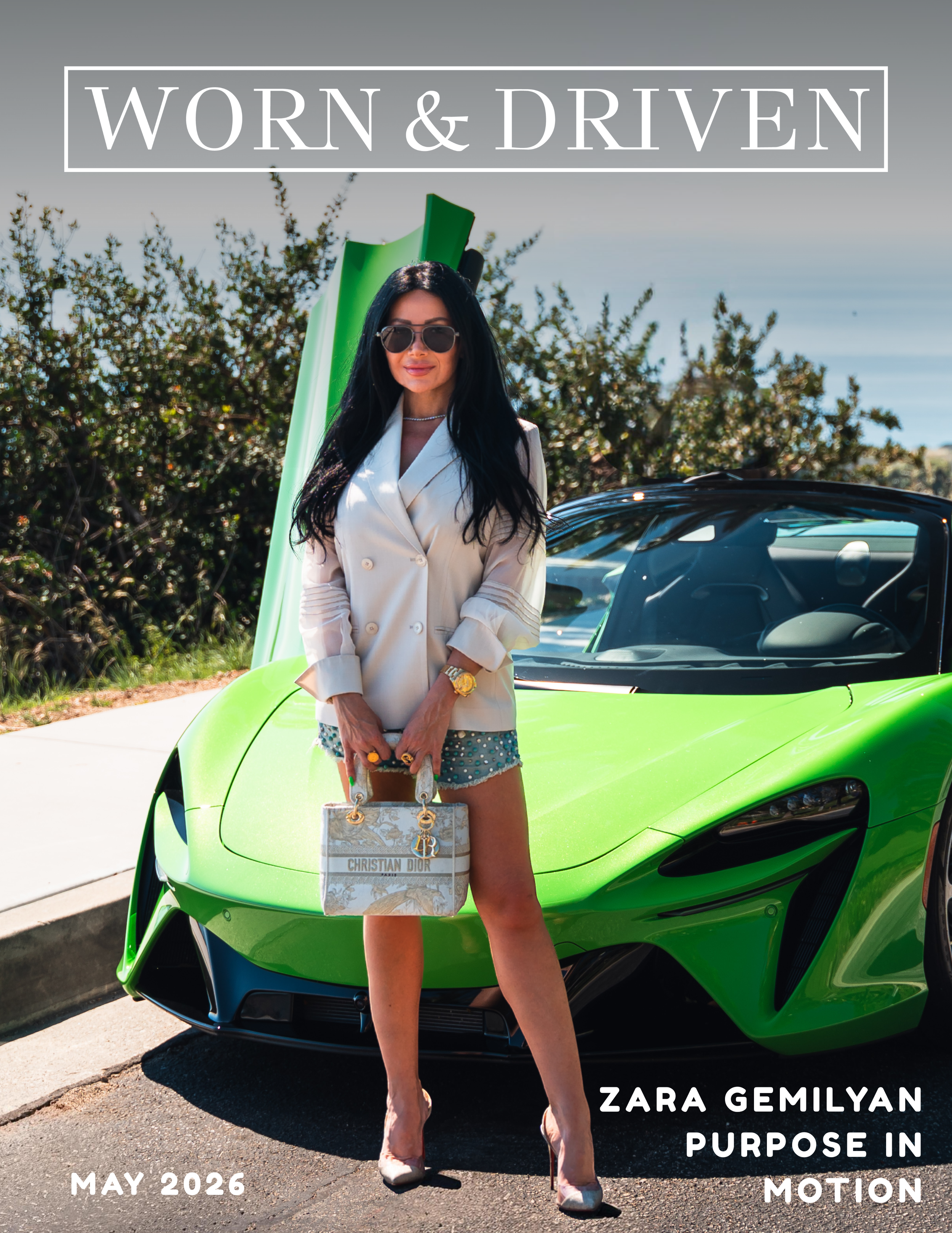 A woman with black hair, sunglasses, white blazer, and shorts standing in front of a bright green sports car with the sky and some trees in the background. Overlaid text reads 'Worn & Driven' at the top, and at the bottom, it says 'Zara Gemilyan Purpose in Motion May 2026'.