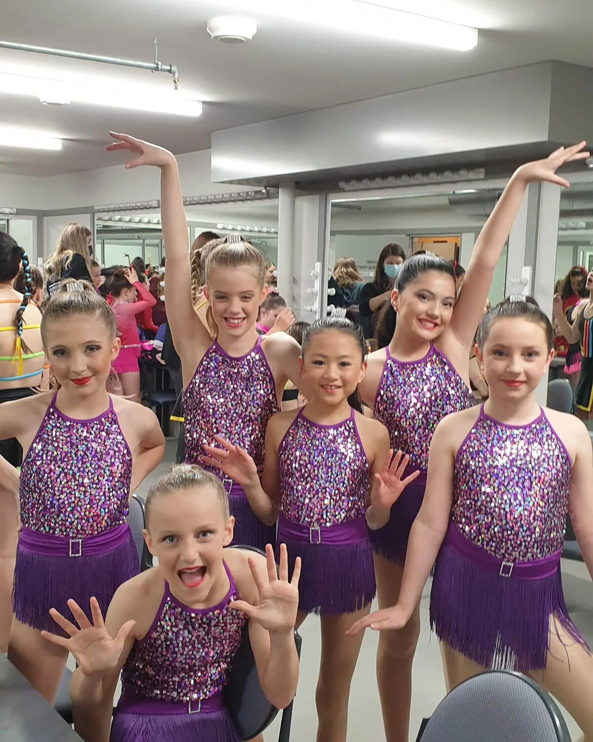Young dancers in purple dance costumes strike a pose in the dressing room