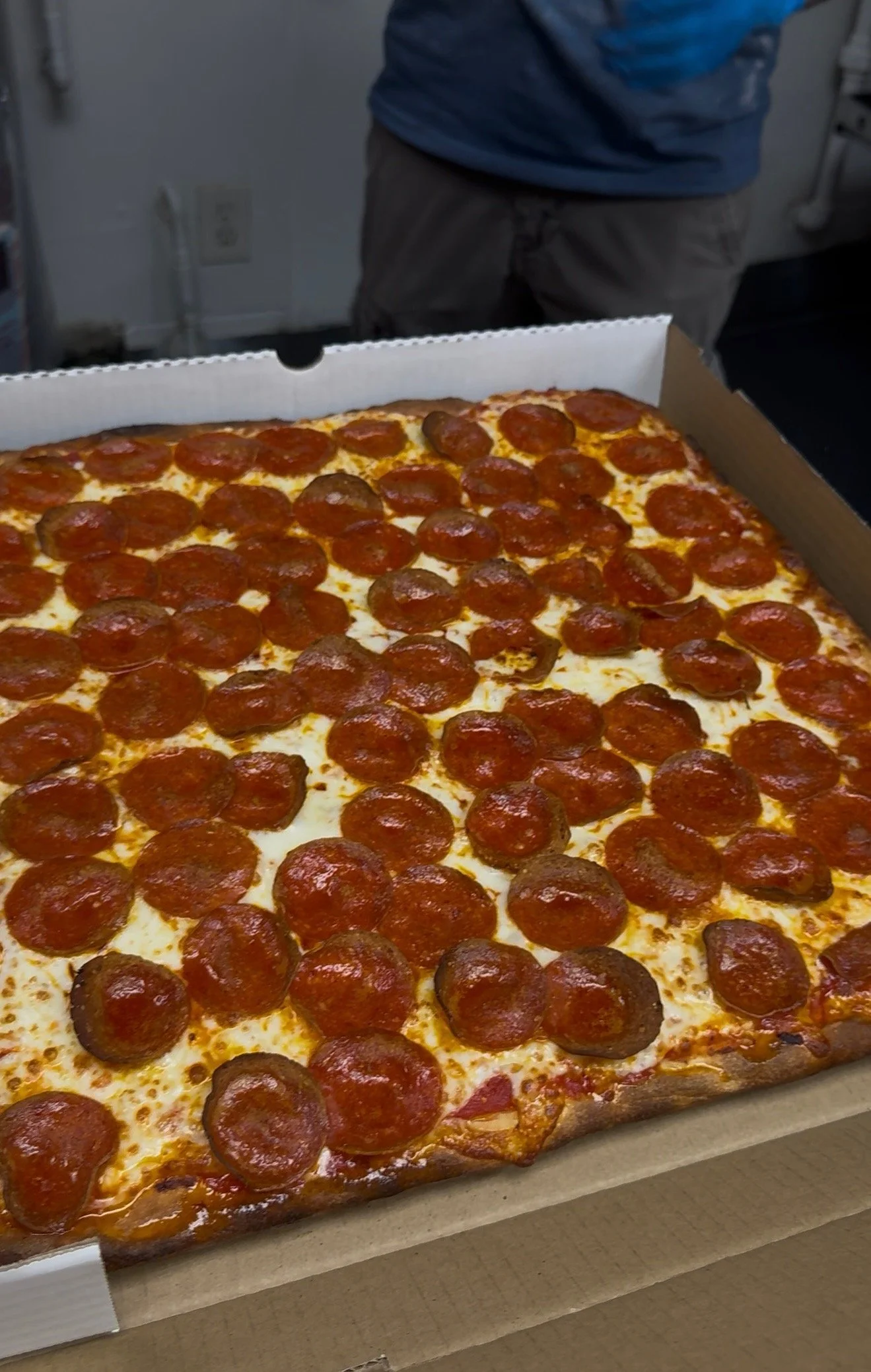 A large pizza with pepperoni slices in a cardboard pizza box.