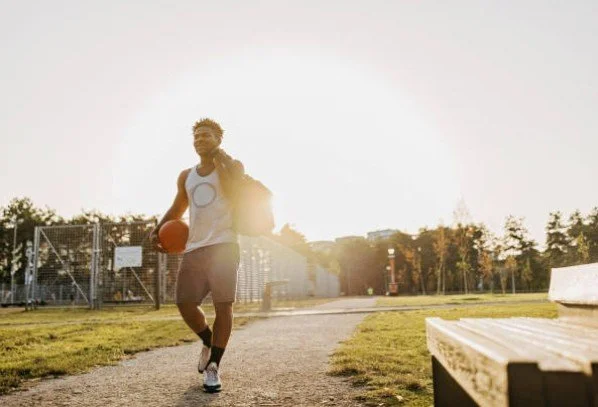 Young man playing football outdoors in a park on a sunny day.