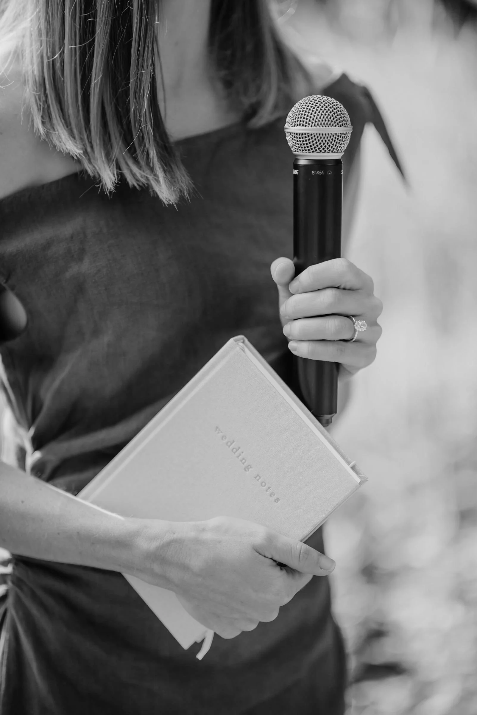 A woman holding a microphone and a wedding notebook