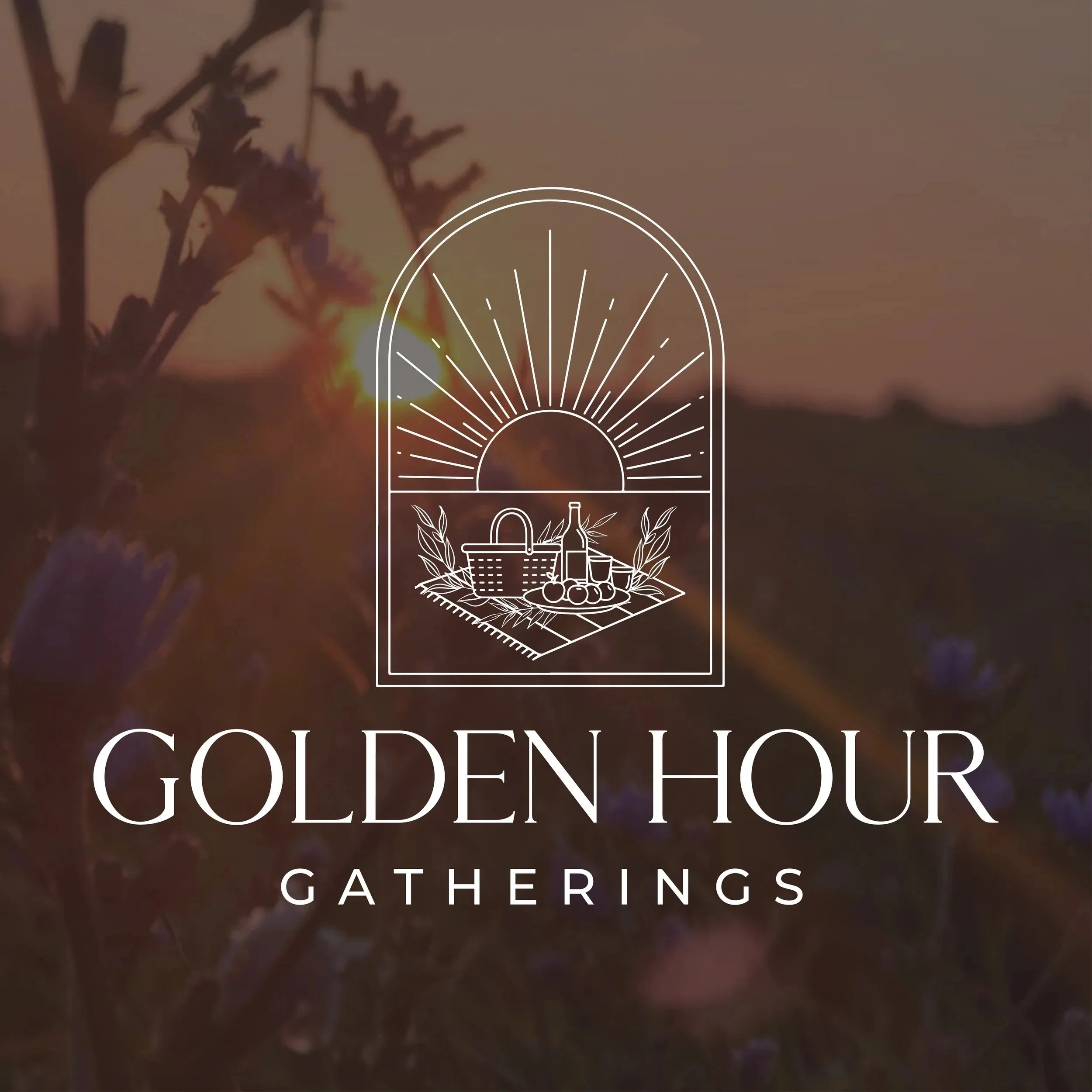 Logo for Golden Hour Gatherings featuring a stylized sun with rays over a picnic basket, bottle, and fruit, with a sunset in the background.