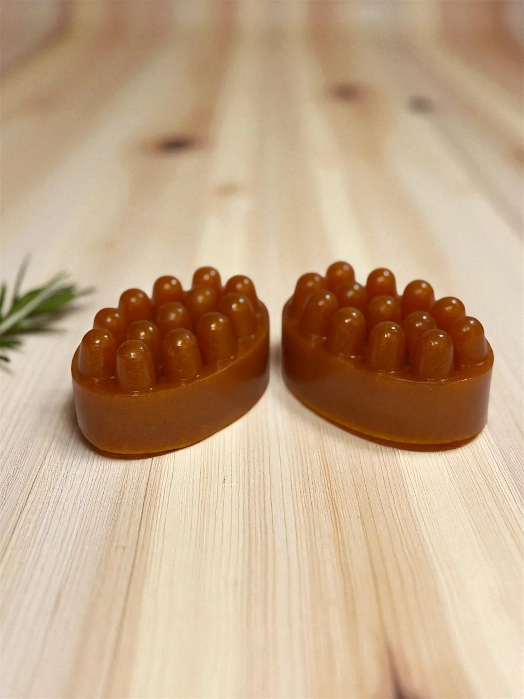 Two brown soap bars with raised bumps on top, placed on a light wooden surface.