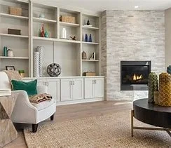 Organized living room with a white bookshelf, a fireplace, an armchair with a green pillow, and a round black coffee table.
