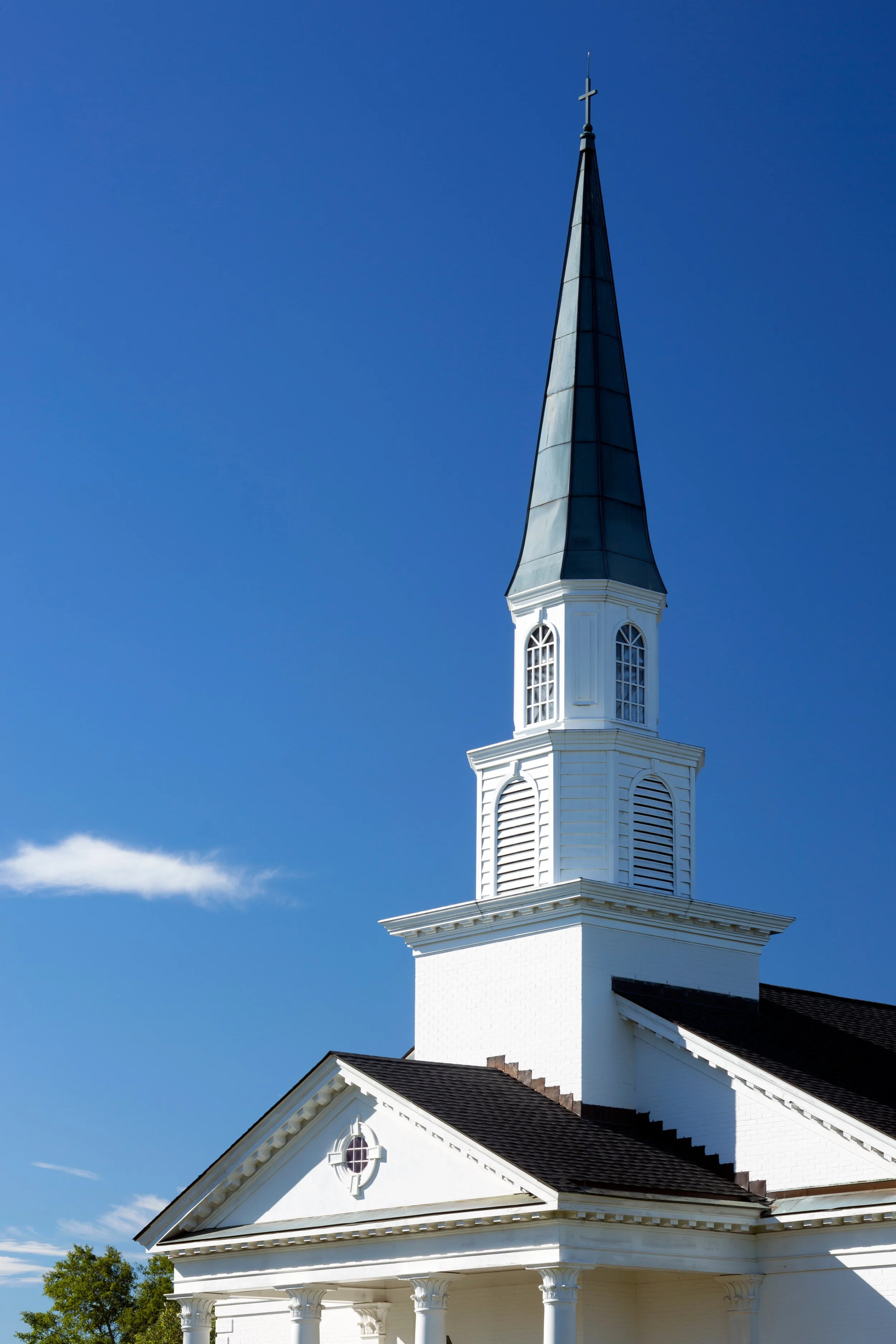 White church with steeple against a blue sky.