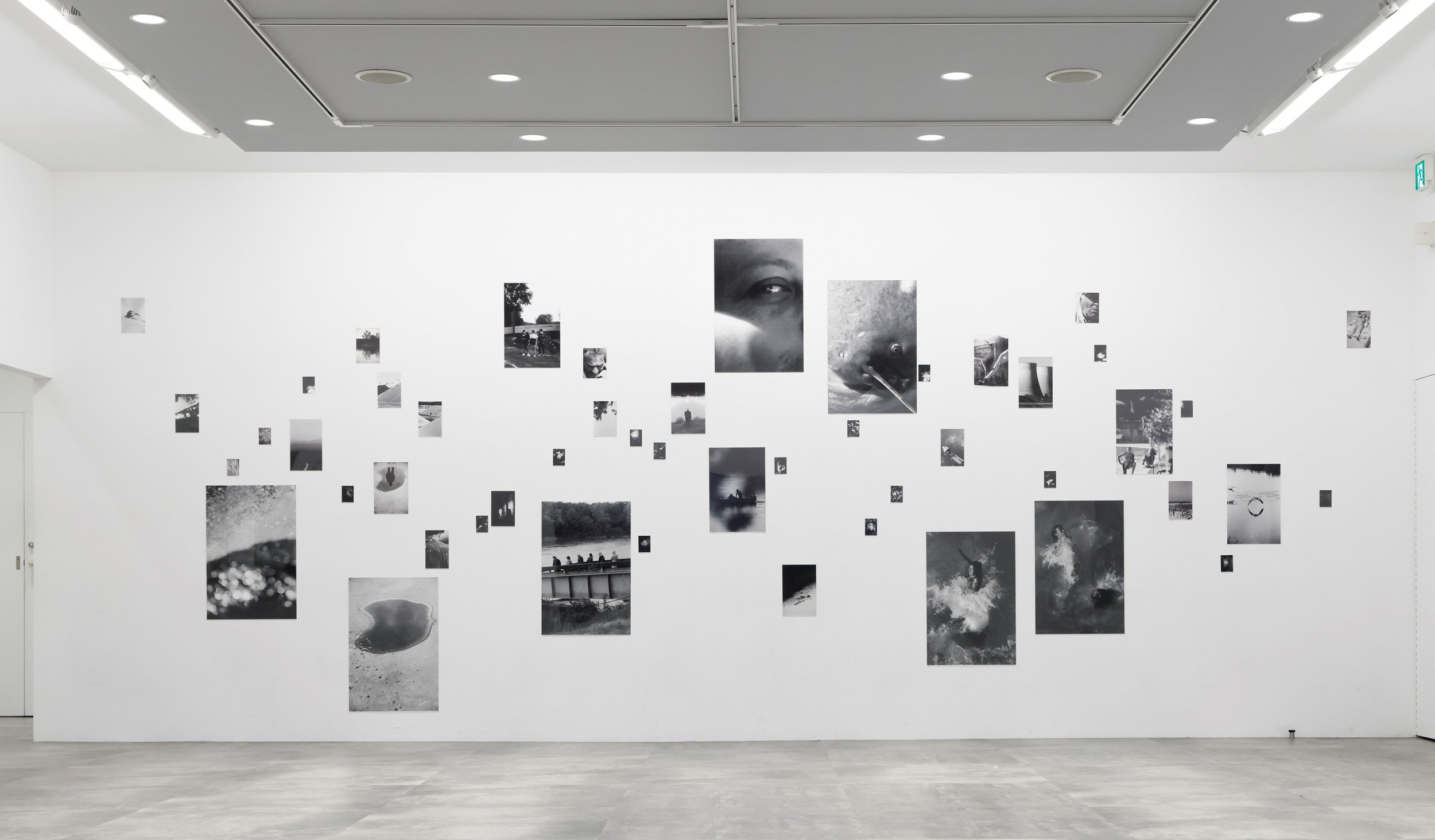 白い壁にさまざまなサイズの黒と白の写真が展示されている現代アートのギャラリー。