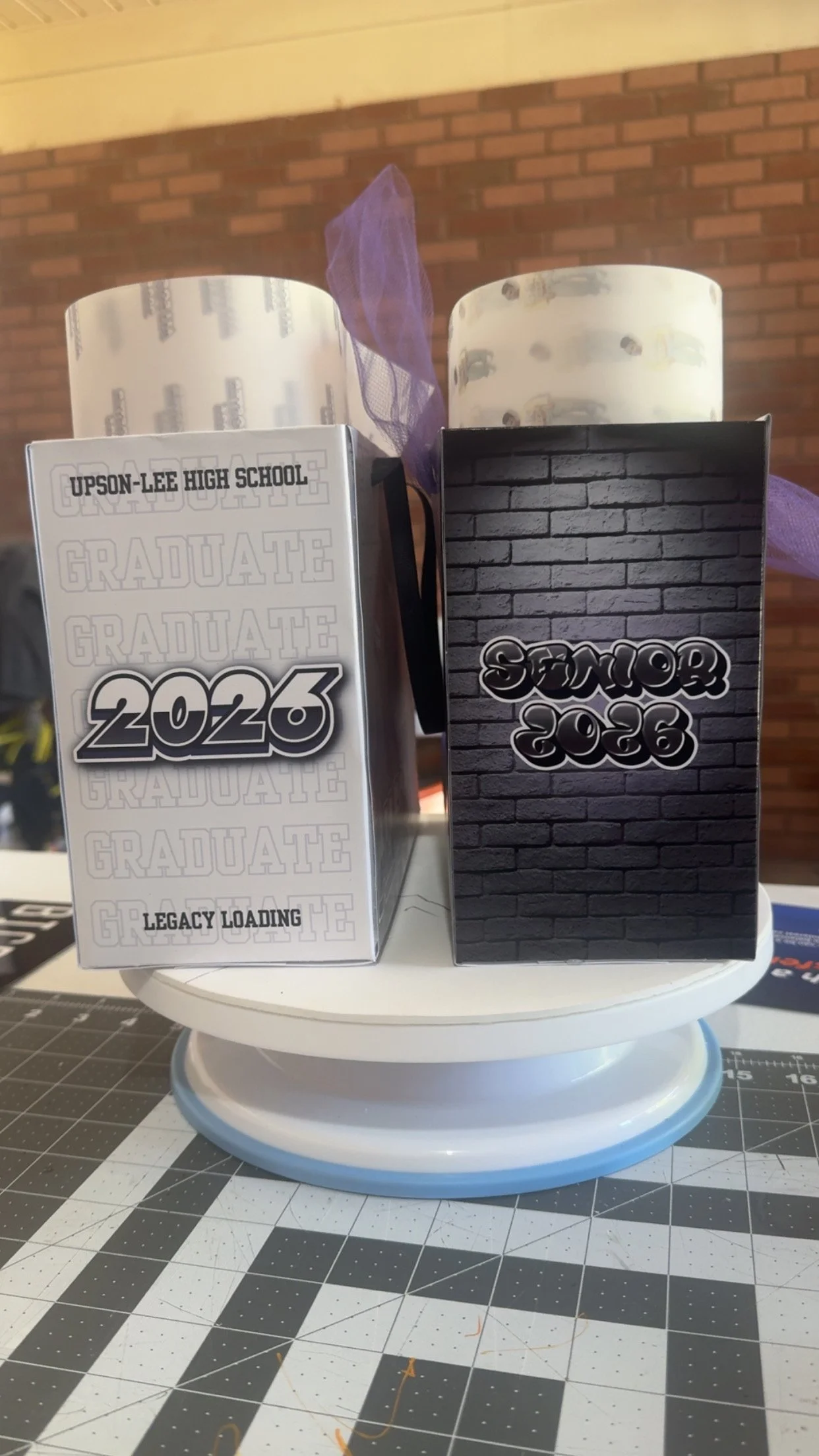 Two commemorative blocks celebrating graduation and senior year, one labeled "Upson-Lee High School Graduate 2026 Legacy Loading" with a white background and the other labeled "Senior 2026" with a dark brick pattern background, both with purple tulle