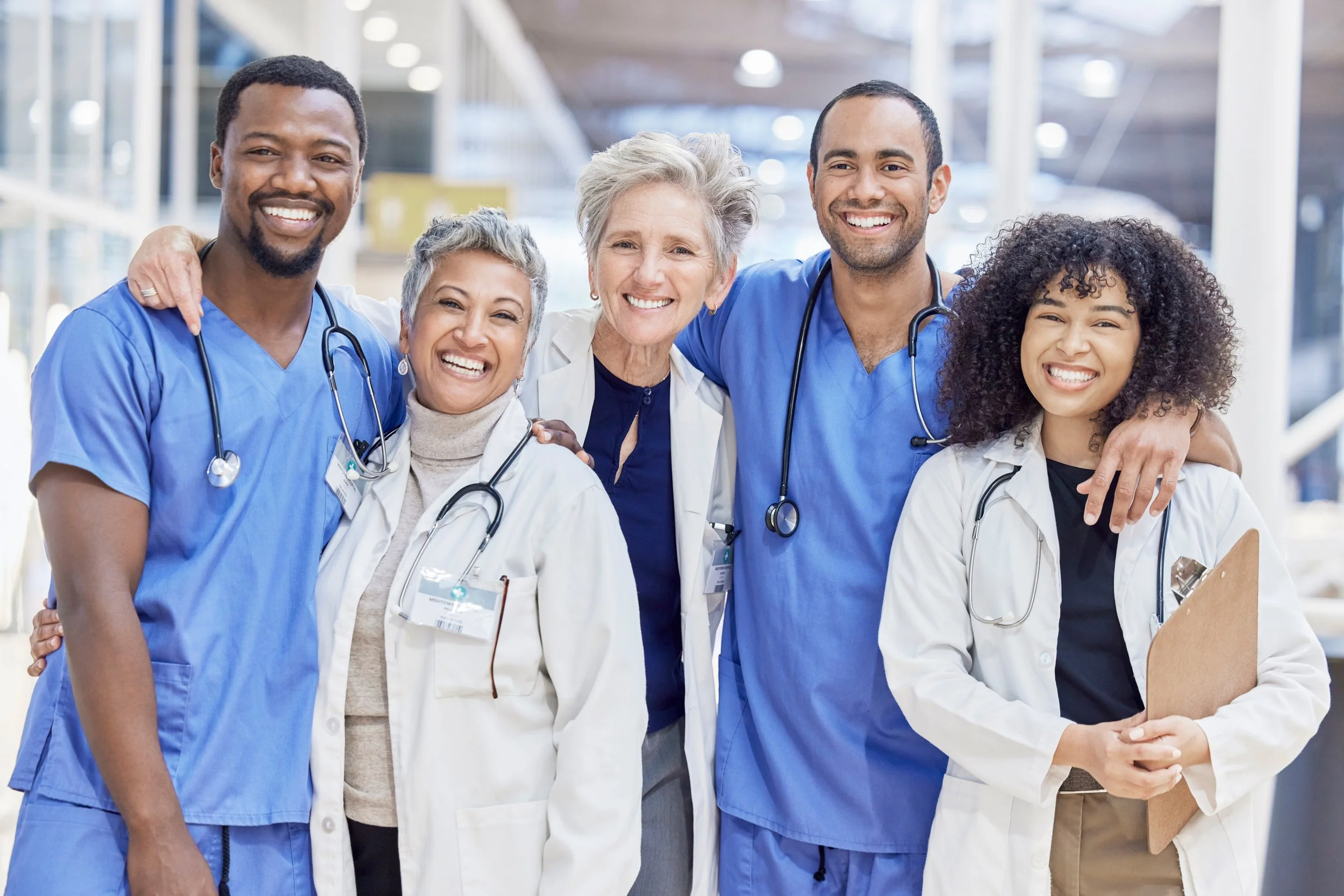 Group of diverse healthcare professionals smiling and posing together in a hospital setting.