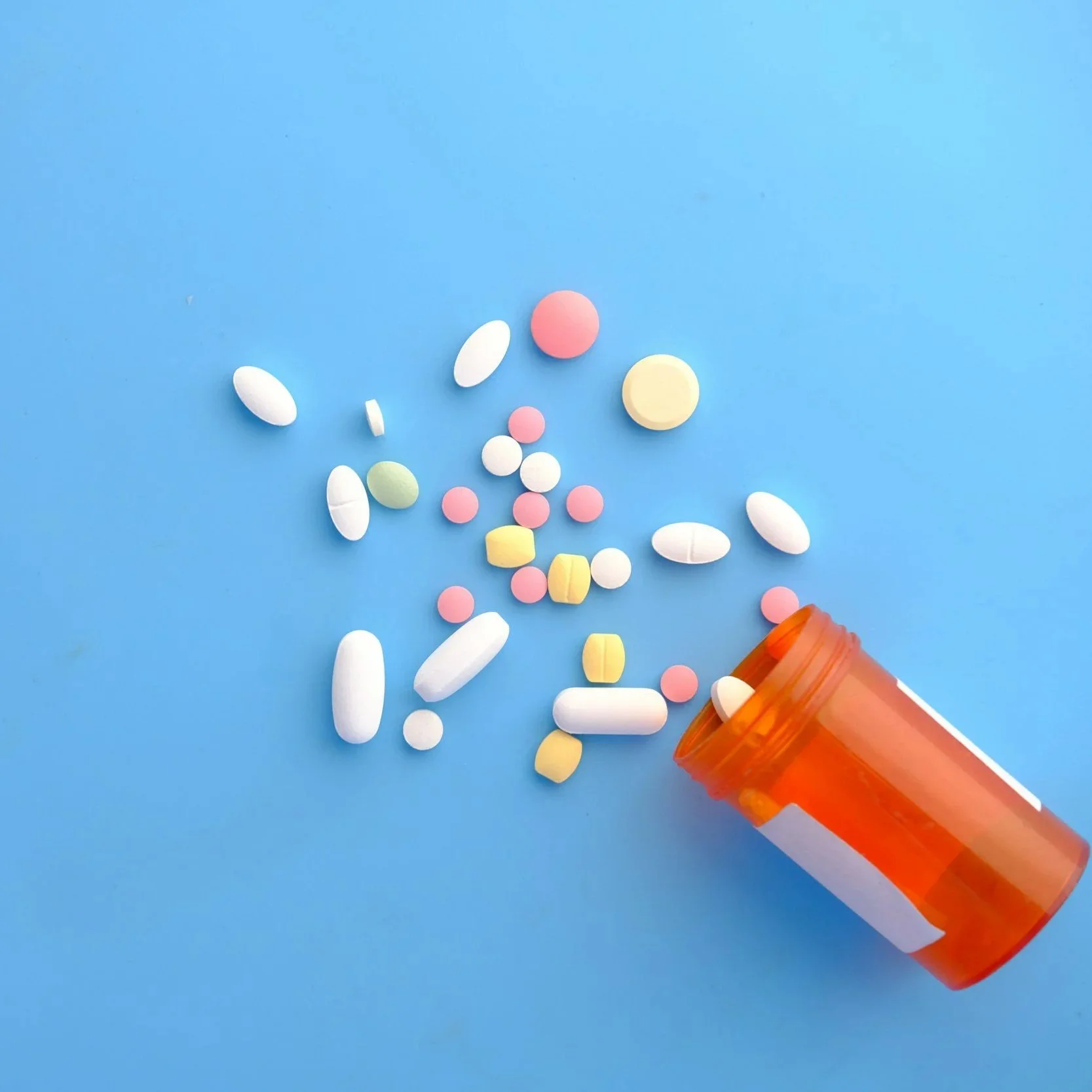 medicine bottle with spilled pills on a blue backbround