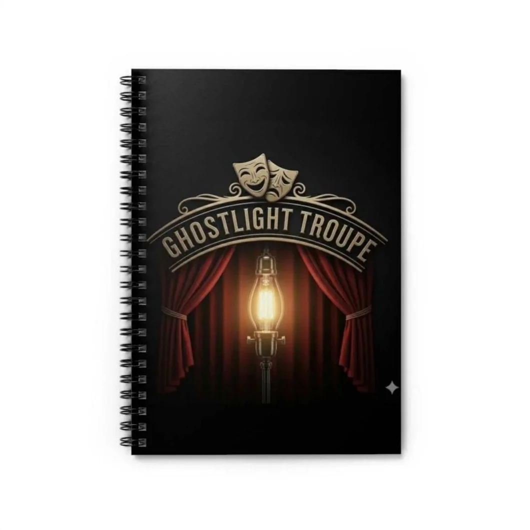 Cover of a notebook with a theatrical theme, featuring a lit lantern, red curtains, and the text 'Ghostlight Troupe' along with comedy and tragedy masks.