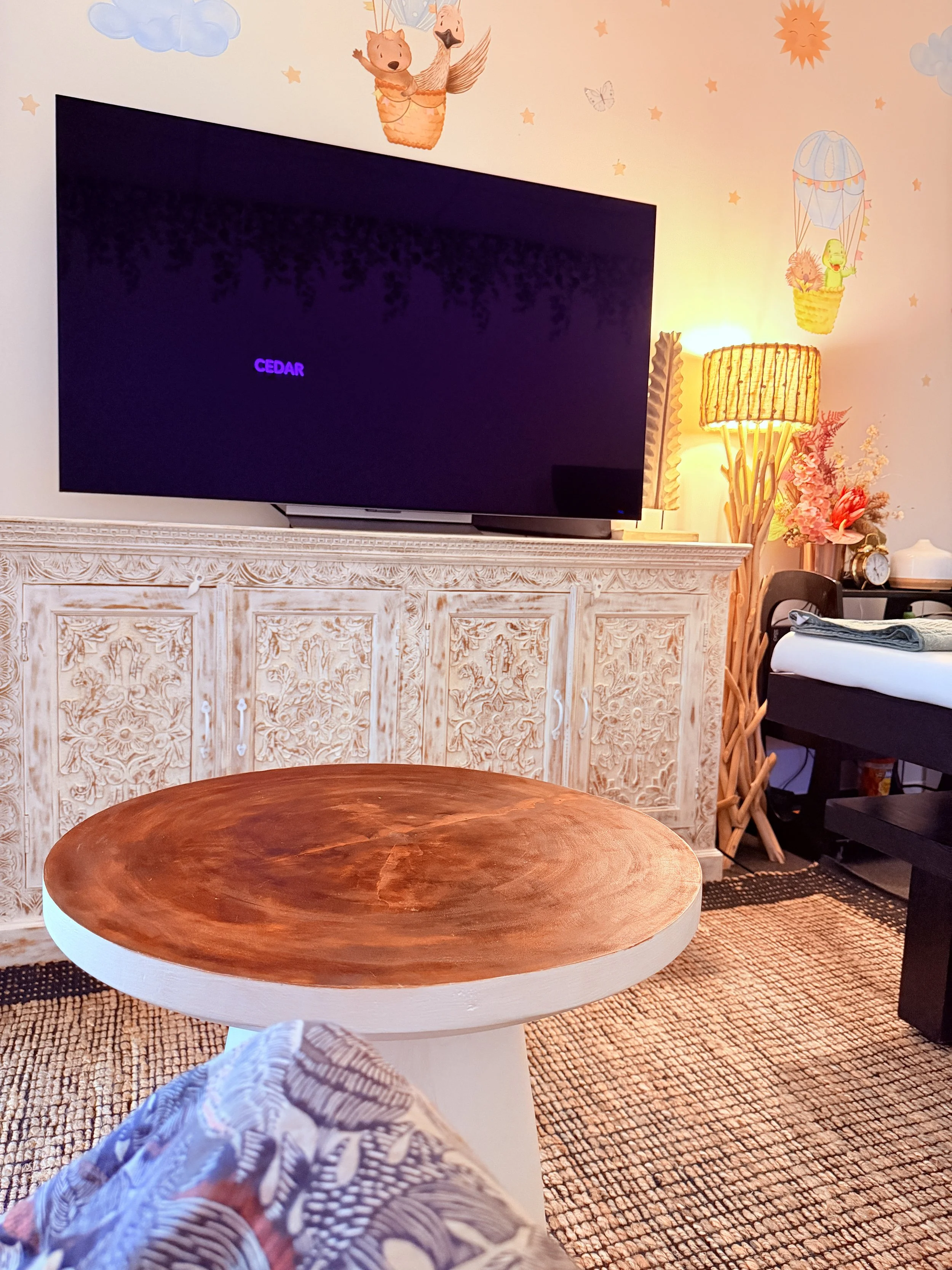 Nature-inspired ultrasound room at Cedar 4D Ultrasound with a large flat-screen display on a wooden cabinet, soft décor, gentle lighting, and a calm, family-friendly bonding environment.