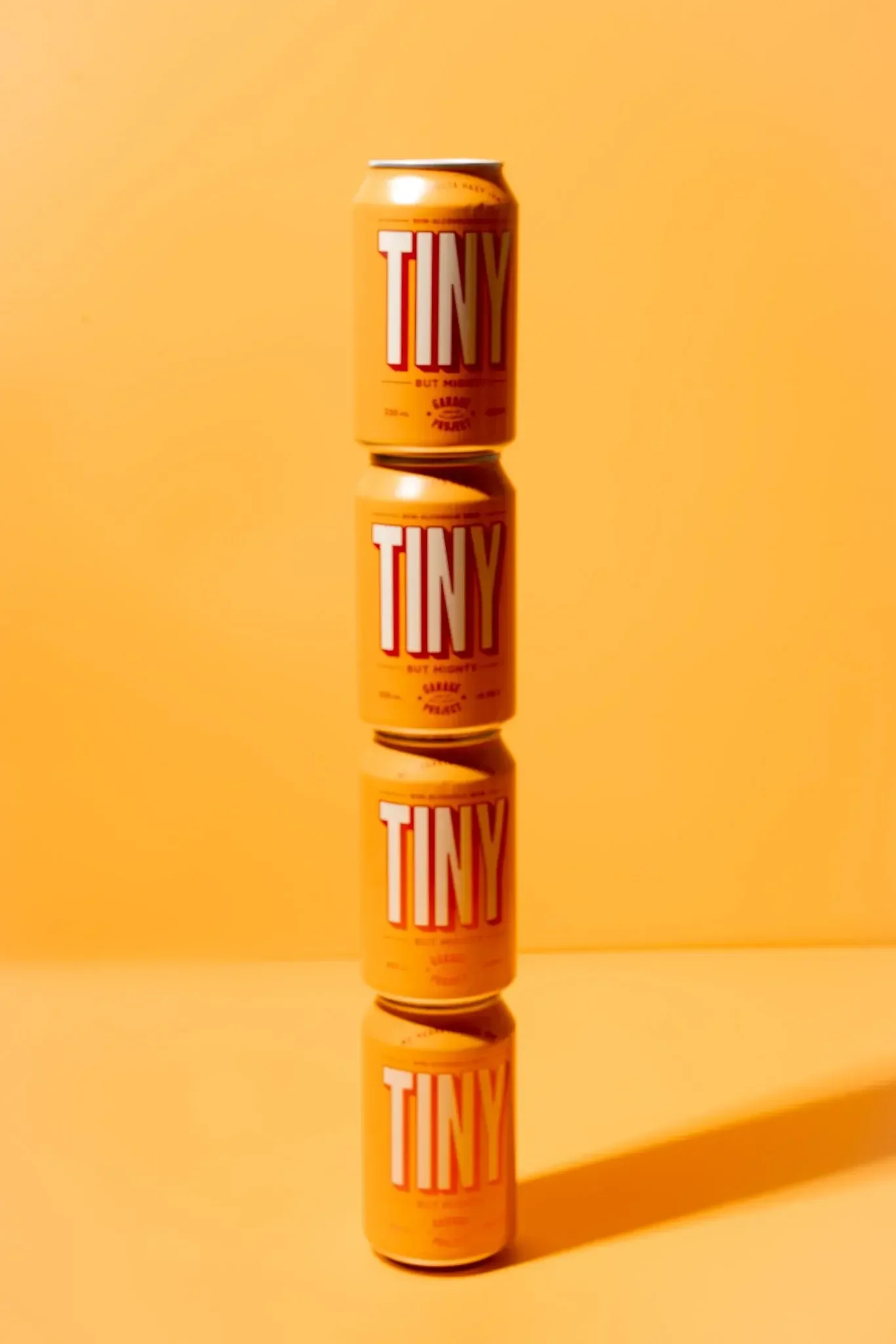 Can of TINY soda sitting on a reflective surface with a yellow background.