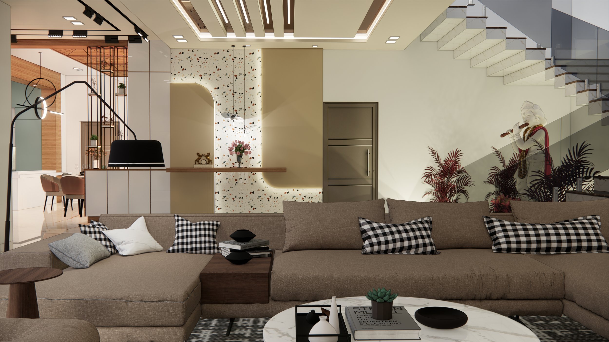 Modern living room with beige sectional sofa, black and white checkered pillows, coffee table with books and decorative items, staircase with glass railing, decorative wall with plants, and a mannequin playing a flute in the background.