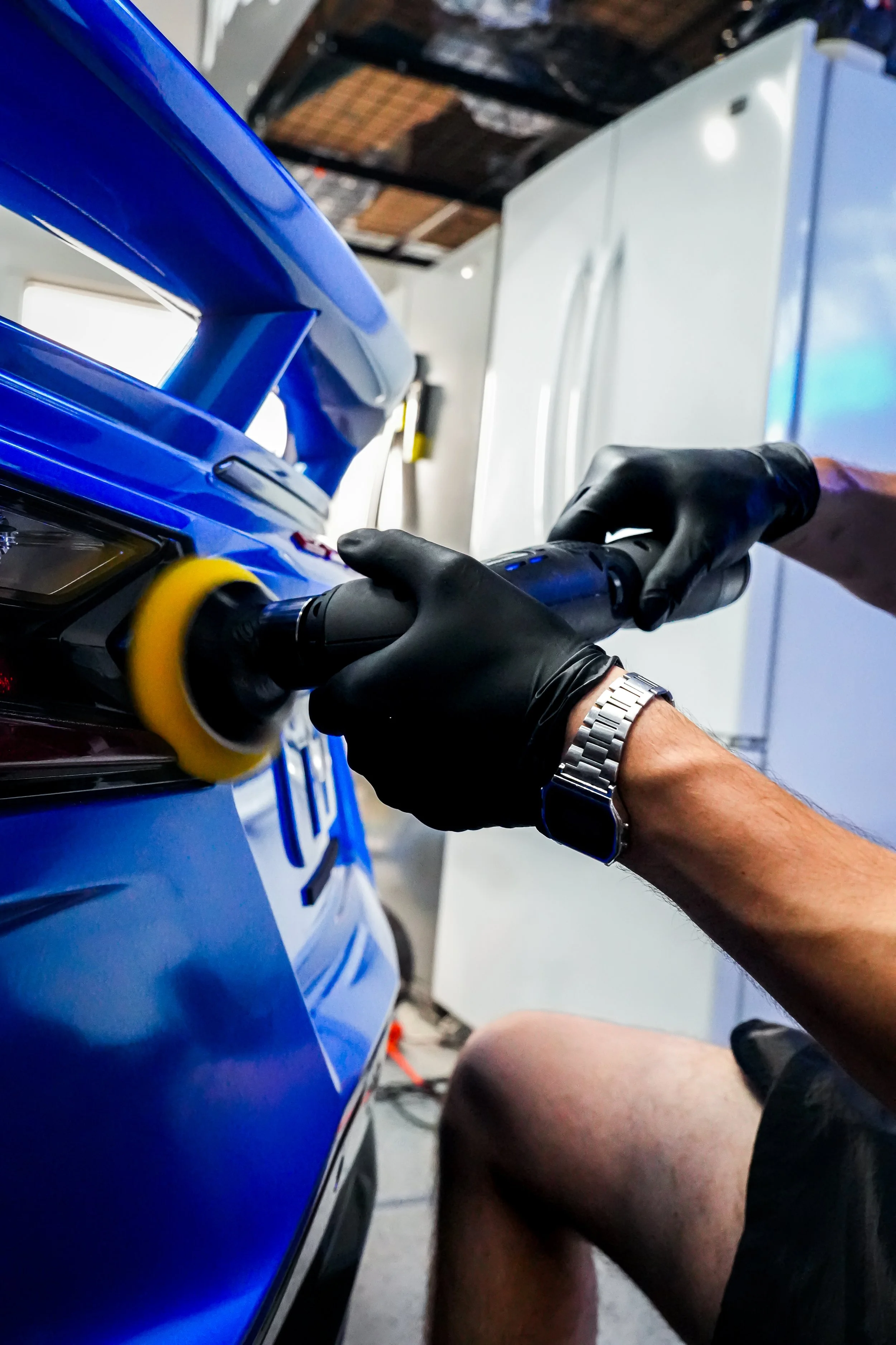 A person polishing a rear bumper