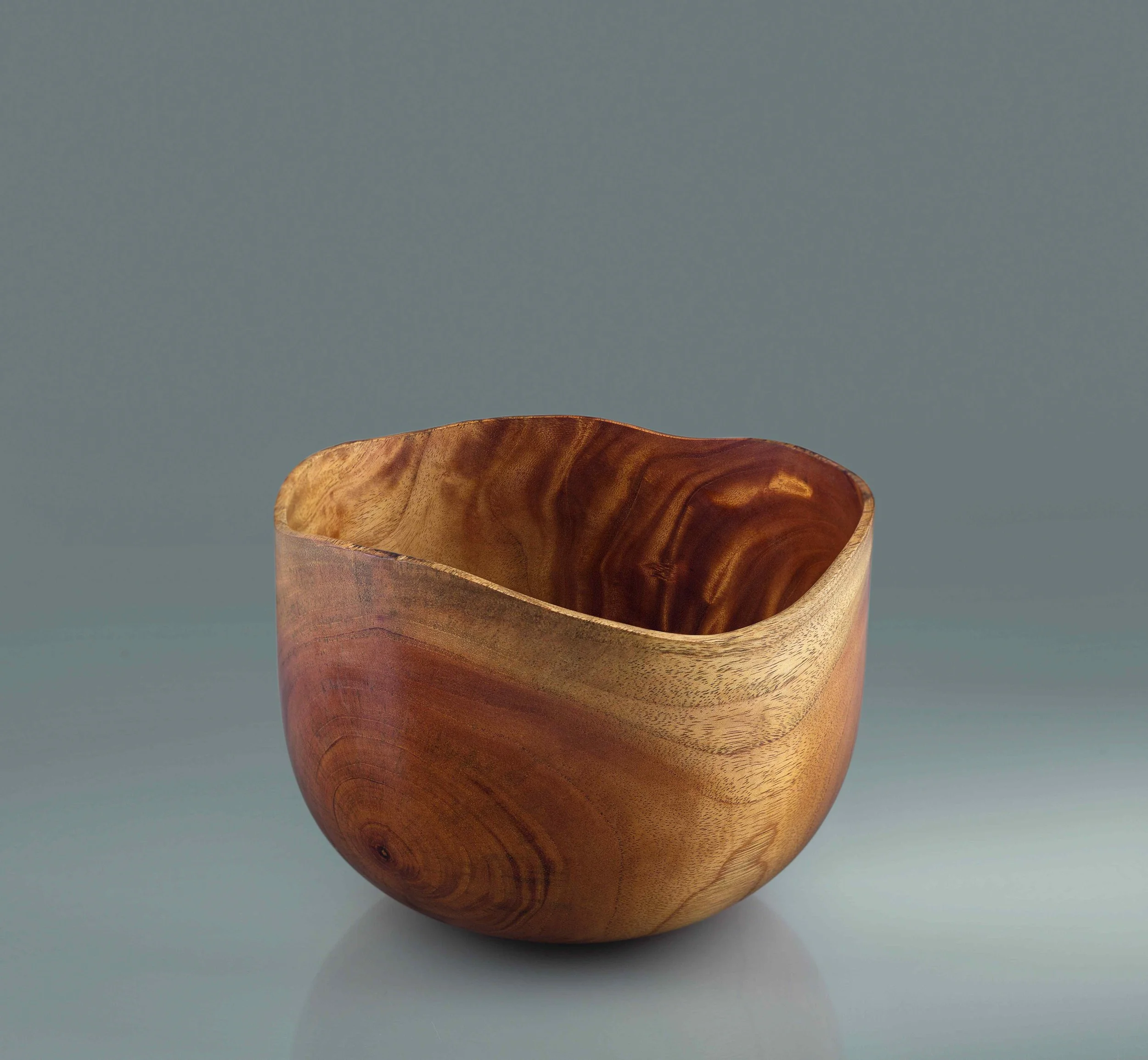 A wooden bowl with a natural finish, showing wood grain patterns, against a plain background.