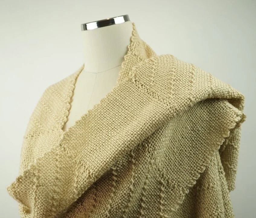 Person weaving fabric on a loom with wooden shuttle and weaving comb.