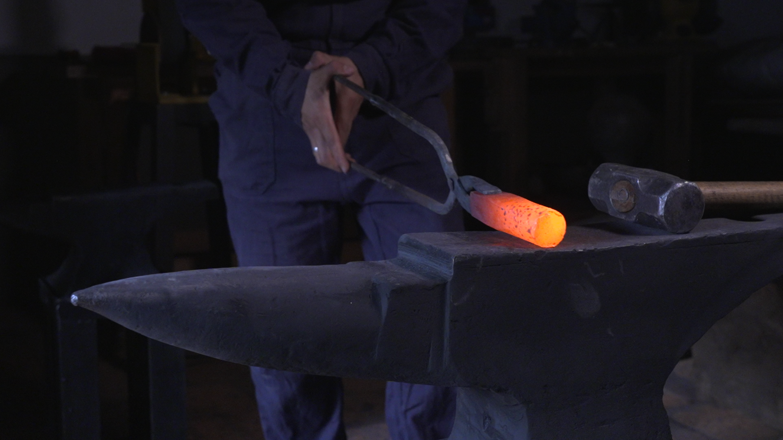 A person using a hammer to work on a large metal pipe attached to a rusted structure.