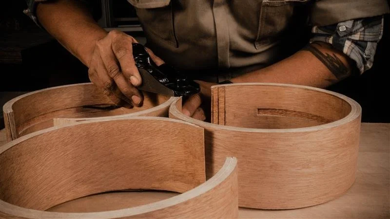 Person carving a decorative swirl design into a wooden surface with a chisel.