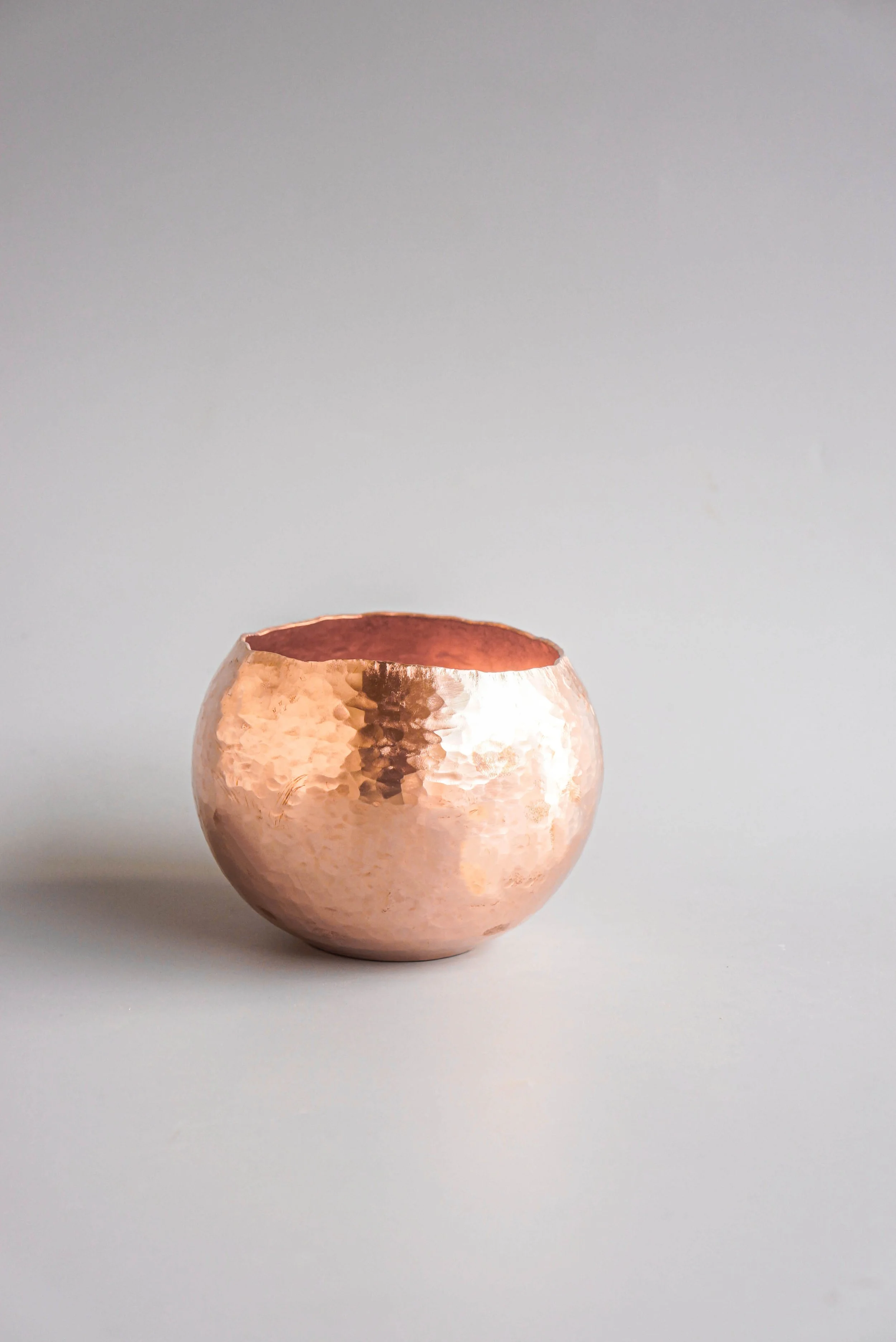 Person using a hammer to shape or work on a long piece of metal or wood, with focus on the person's hands and the tool.