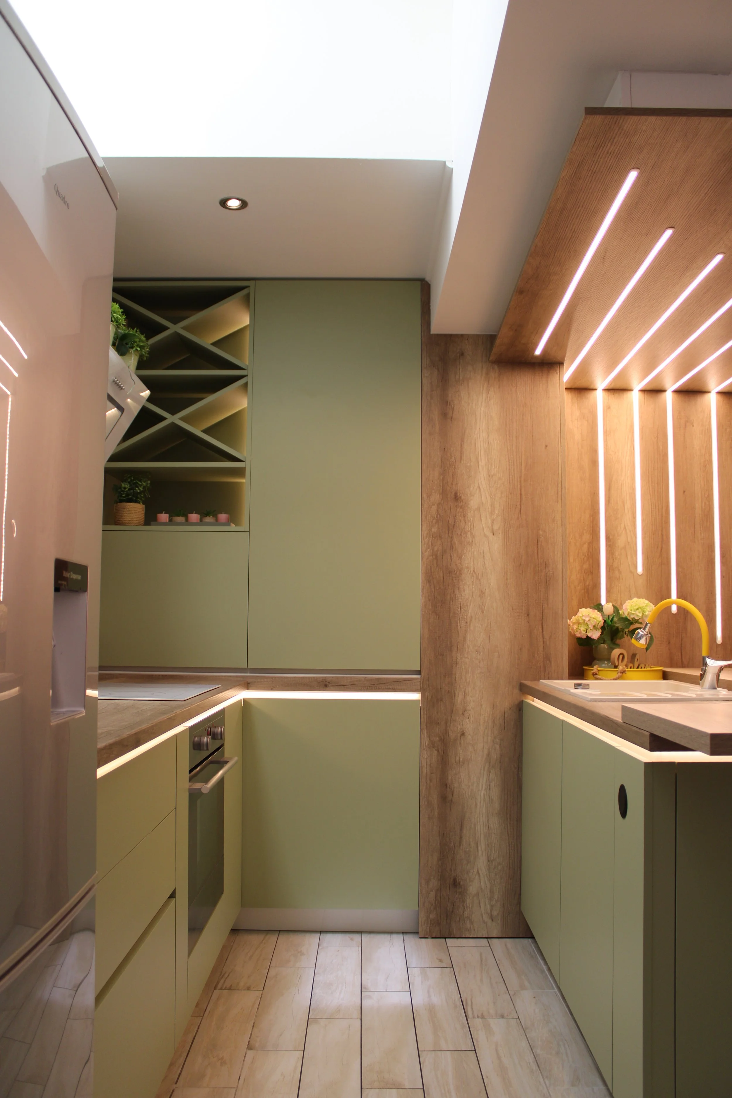 Small modern kitchen with matte green cabinets, built-in oven, wood accents and open wine rack, custom design by Bespoke Interijeri.