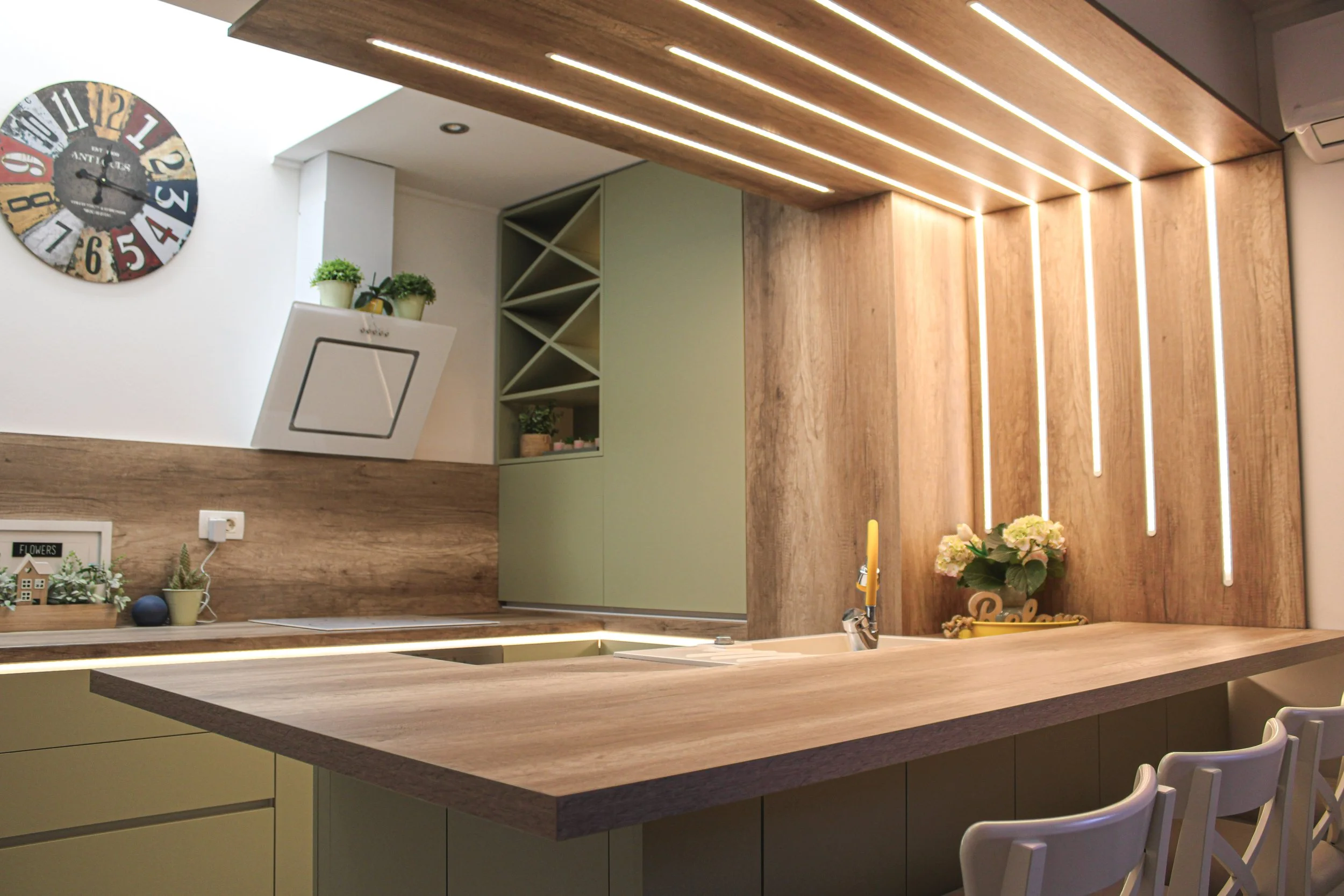 Small modern kitchen with matte green cabinets, built-in oven, wood accents and open wine rack, custom design by Bespoke Interijeri.
