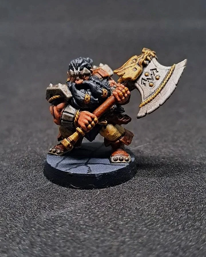 Miniaturfigur eines Zwergen mit Keule auf schwarzem Hintergrund.