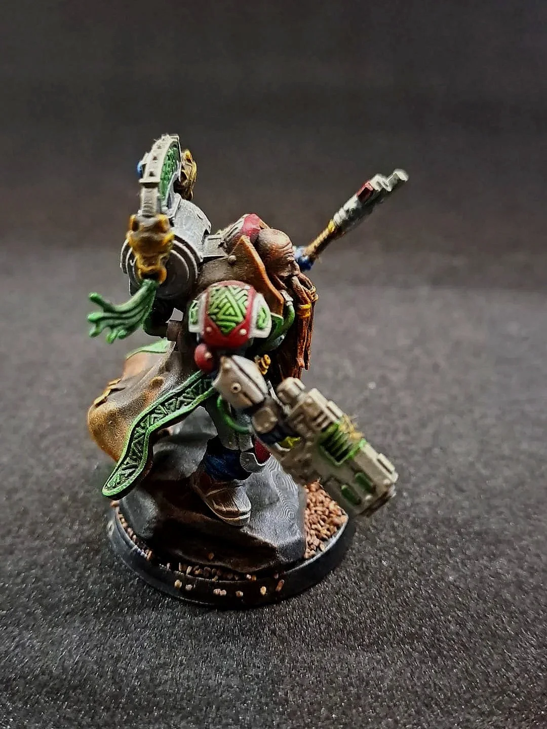 Ein detailreicher, von Hand bemalter Miniaturfigur aus einem Science-Fiction-Theme, die einen bewaffneten Krieger zeigt, der auf einem schwarzen Untergrund steht.