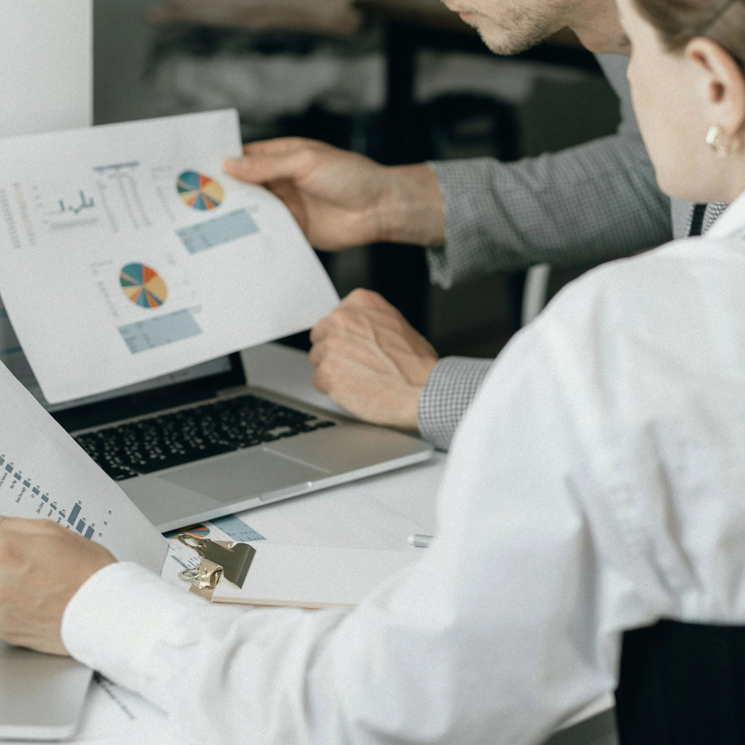 Deux personnes regardent des graphiques à l'aide de documents et d'un ordinateur portable dans un bureau