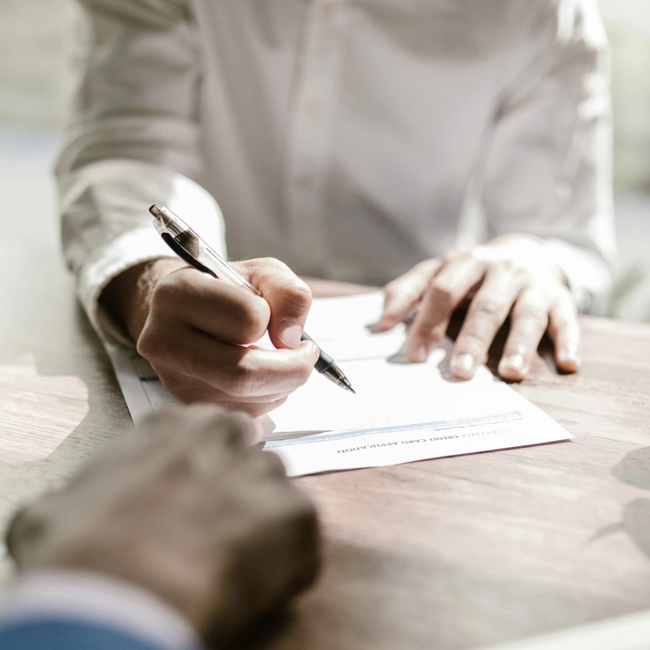 Une personne est en train de signer un document avec un stylo.