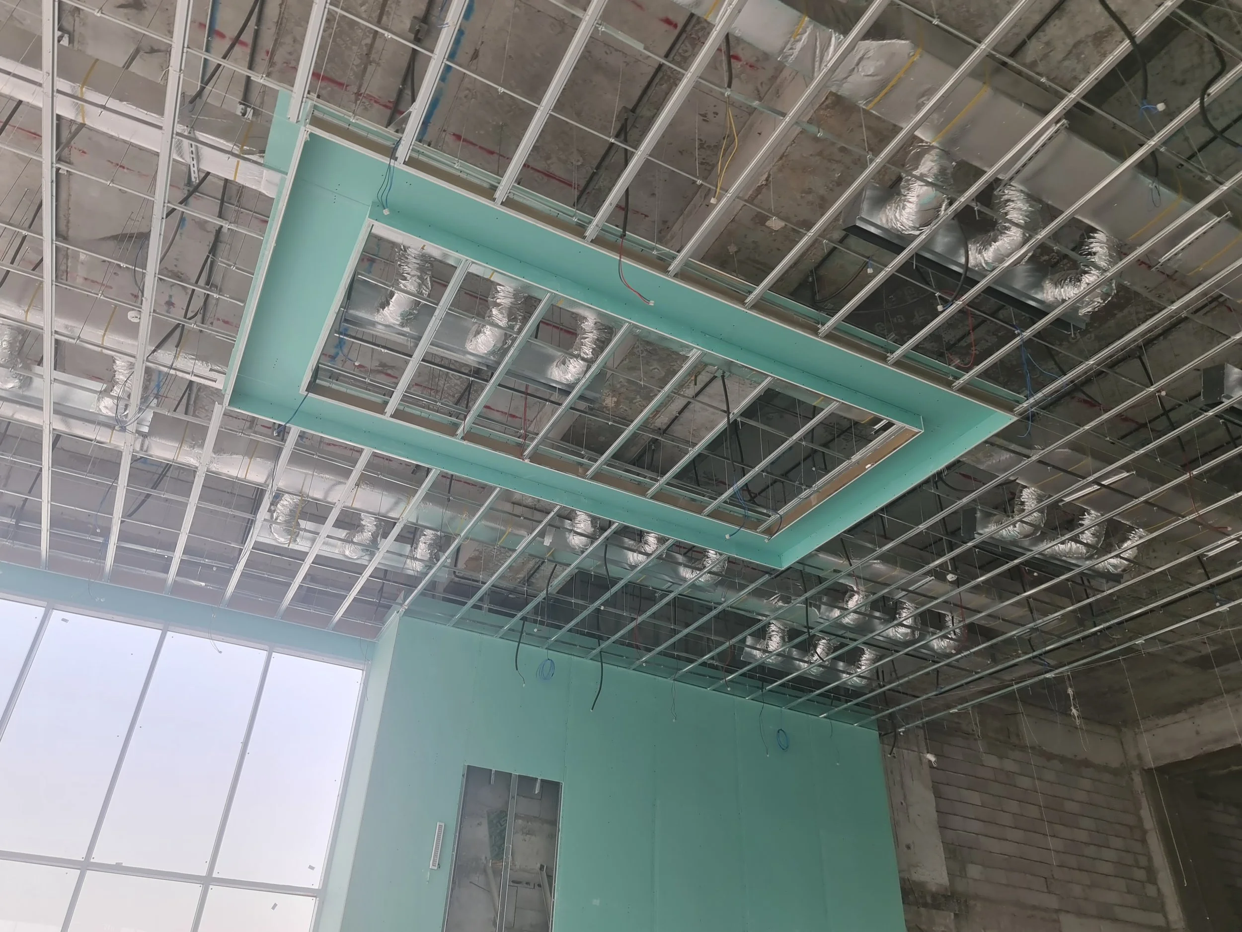 Ceiling construction with metal framework, ductwork, and wiring in a building under renovation or construction.
