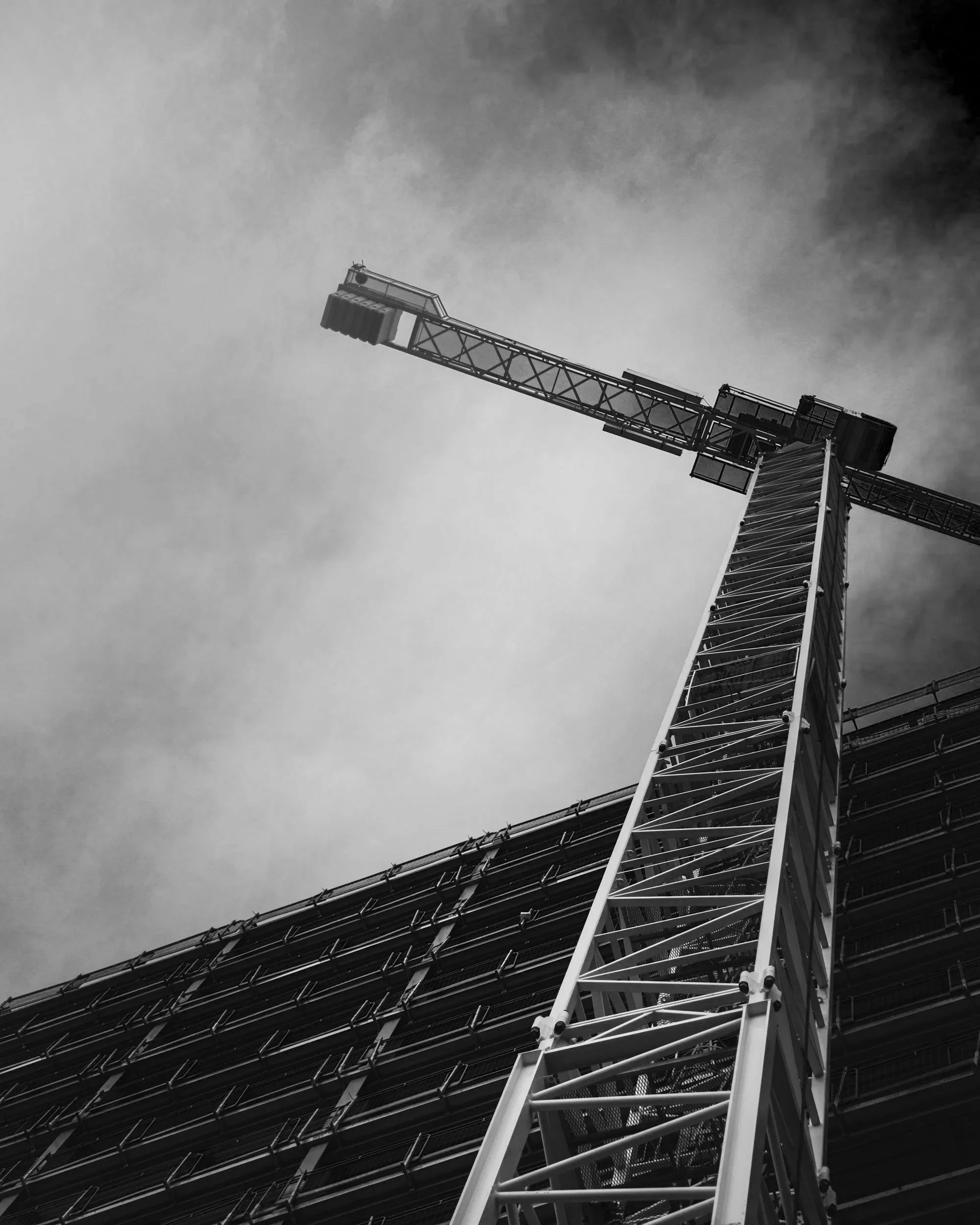 Black and white photo of a construction crane and scaffolding on a building under construction