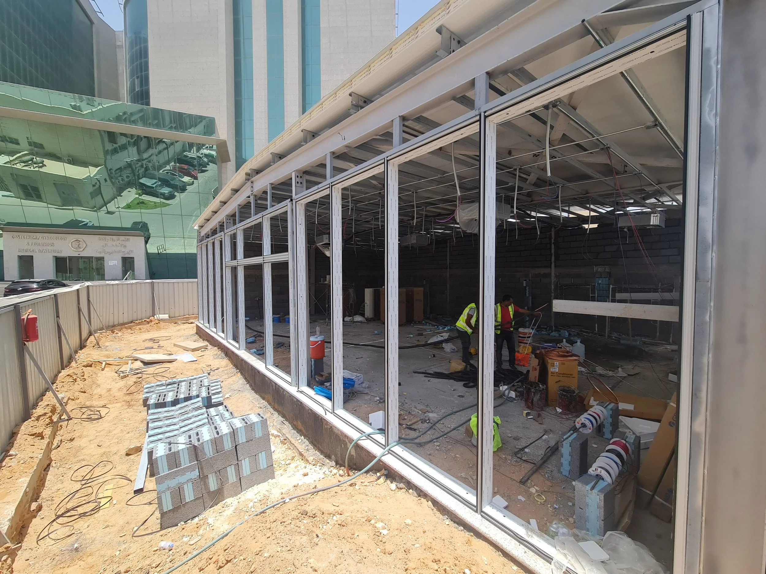 Construction workers installing glass windows at a building site in an urban area.